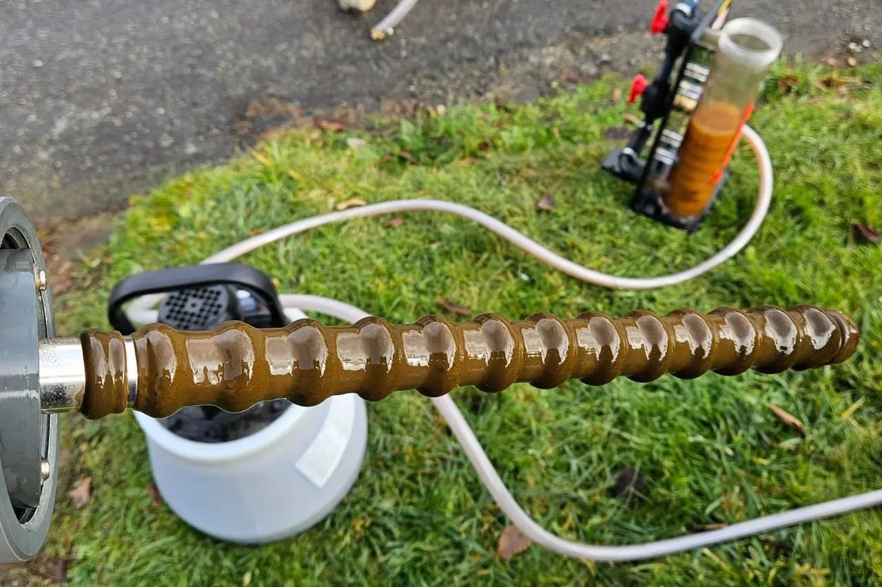 Tyč filtru obalená kalem z otopné soustavy, v pozadí proplachovací stroj